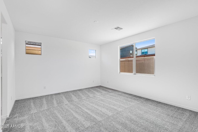 unfurnished room featuring carpet, visible vents, and baseboards