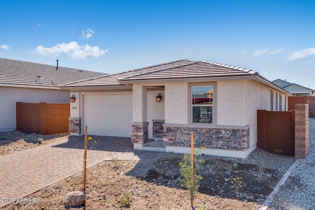 view of front facade featuring a garage, stone siding, fence, decorative driveway, and stucco siding