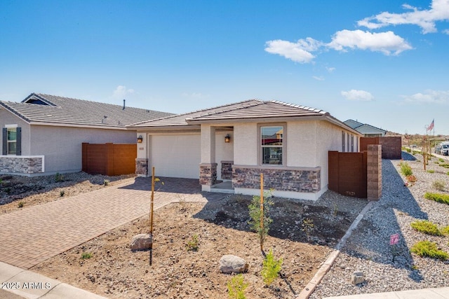 view of front of house featuring an attached garage, stone siding, decorative driveway, and stucco siding