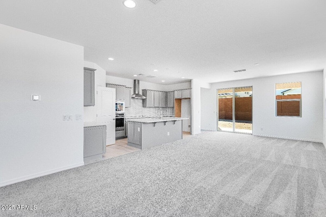 kitchen with wall chimney exhaust hood, gray cabinets, oven, and light colored carpet