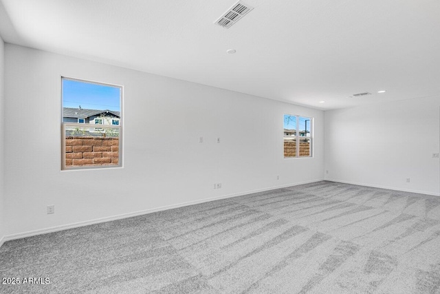 spare room with carpet floors, visible vents, and baseboards