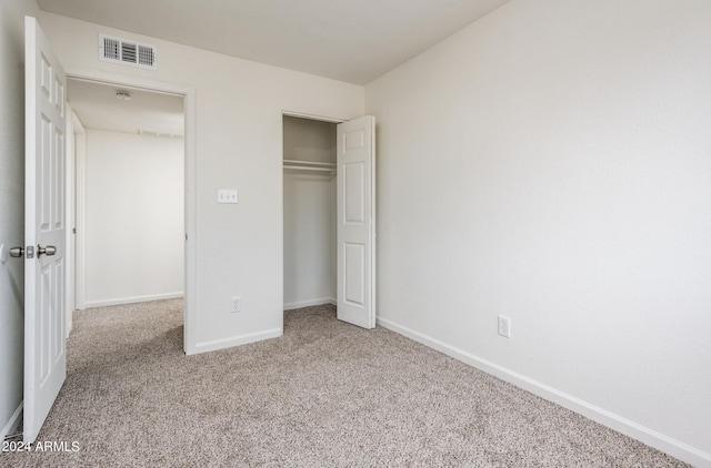 unfurnished bedroom featuring a closet and light colored carpet