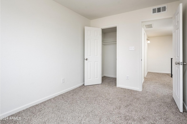 unfurnished bedroom featuring light colored carpet and a closet