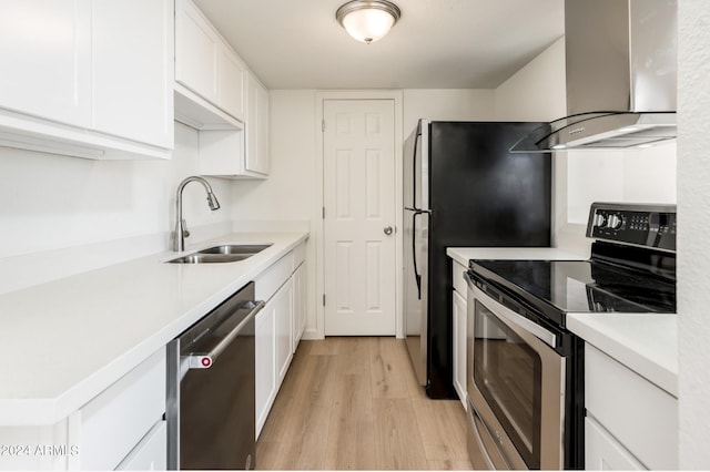 kitchen featuring stainless steel appliances, white cabinets, sink, light wood-type flooring, and wall chimney exhaust hood