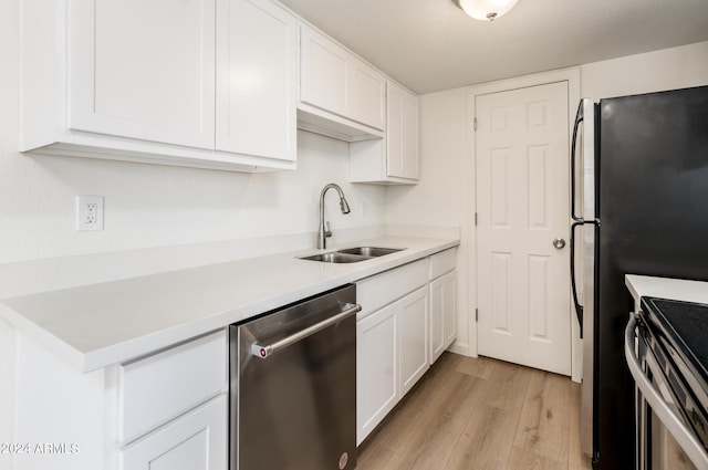 kitchen with sink, stainless steel dishwasher, white cabinetry, and light wood-type flooring