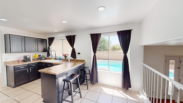 8541 W Pershing Ave, Peoria, AZ 85381 - kitchen with a kitchen bar, light tile patterned floors, a peninsula, light countertops, and recessed lighting
