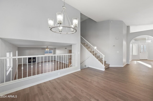 interior space with high vaulted ceiling, wood-type flooring, and ceiling fan with notable chandelier