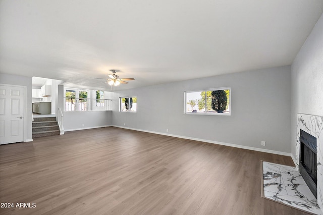 unfurnished living room featuring hardwood / wood-style flooring, ceiling fan, a fireplace, and a wealth of natural light