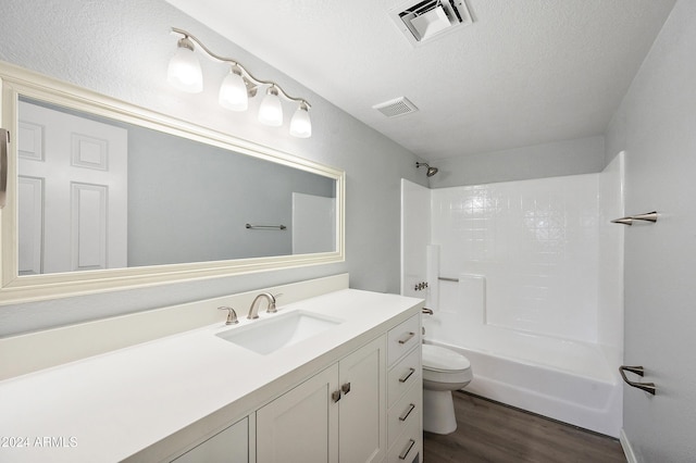 full bathroom featuring vanity, a textured ceiling, shower / bathing tub combination, hardwood / wood-style flooring, and toilet