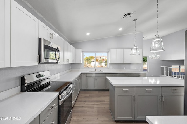 kitchen featuring stainless steel appliances, sink, hardwood / wood-style flooring, gray cabinets, and lofted ceiling