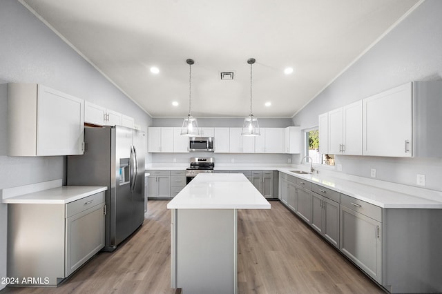 kitchen with a center island, stainless steel appliances, lofted ceiling, and gray cabinetry