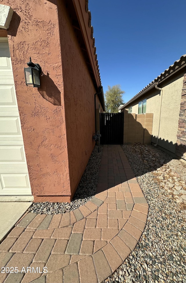 view of home's exterior featuring a tile roof, fence, and stucco siding