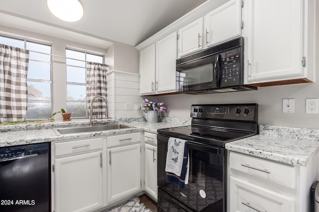 kitchen with lofted ceiling, black appliances, sink, and white cabinetry