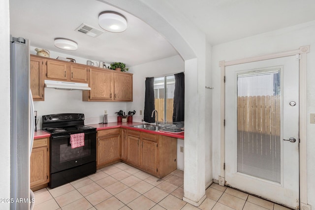 kitchen with light tile patterned flooring, a healthy amount of sunlight, stainless steel fridge, and black / electric stove