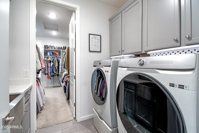 laundry room with cabinets, washing machine and clothes dryer, and light hardwood / wood-style floors