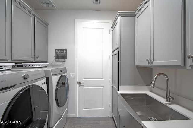 laundry area with cabinets, separate washer and dryer, and sink