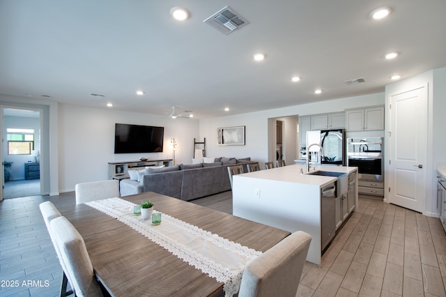 dining area with ceiling fan, sink, and light hardwood / wood-style flooring