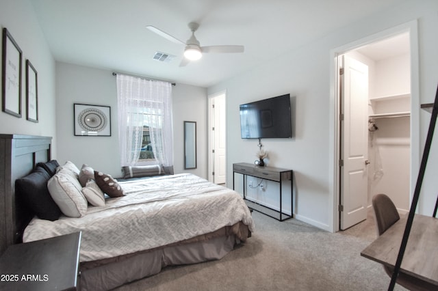 bedroom featuring a spacious closet, light carpet, and ceiling fan