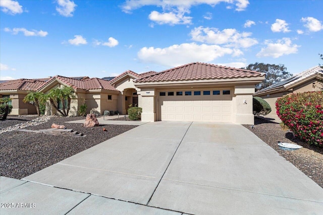 mediterranean / spanish home featuring concrete driveway, a tiled roof, an attached garage, and stucco siding