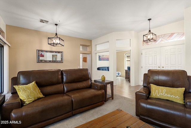 living room with a chandelier, visible vents, and light colored carpet