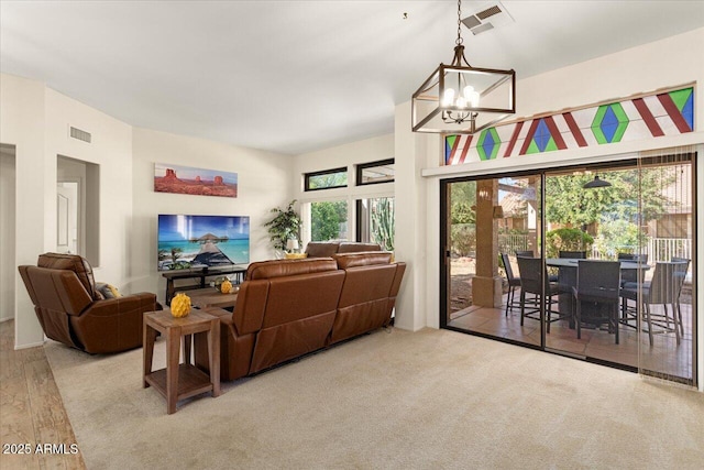 living room with a chandelier, visible vents, and light carpet