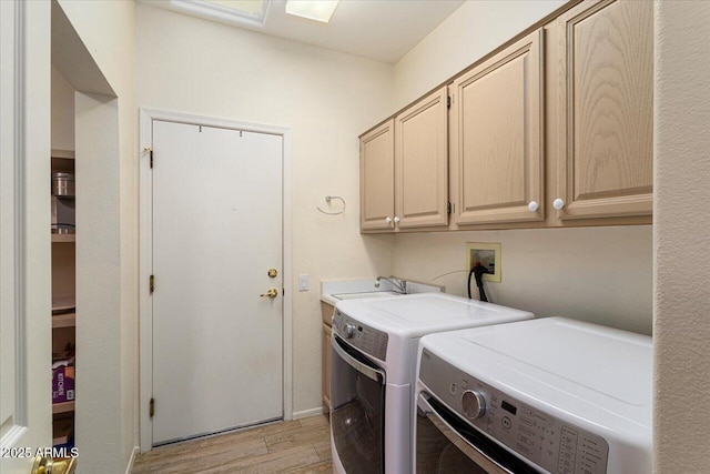 washroom with light wood-style floors, washer and dryer, cabinet space, and a sink