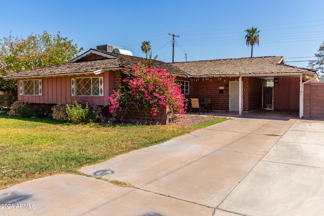 ranch-style home featuring a front lawn and a carport