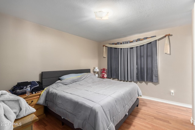 bedroom with a textured ceiling and light hardwood / wood-style flooring