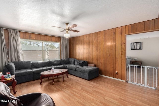 living room with a textured ceiling, ceiling fan, and light hardwood / wood-style floors