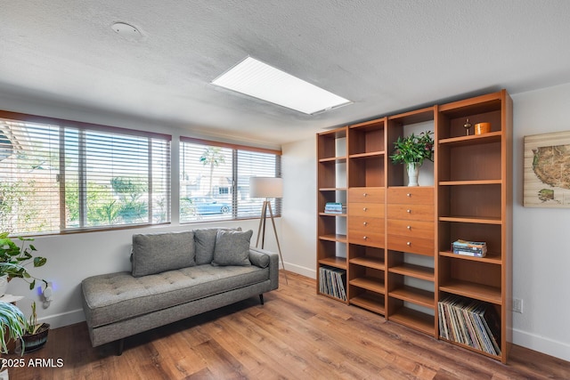 sitting room featuring a healthy amount of sunlight, a skylight, and hardwood / wood-style flooring