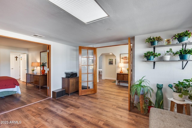 interior space with a textured ceiling, french doors, and hardwood / wood-style floors