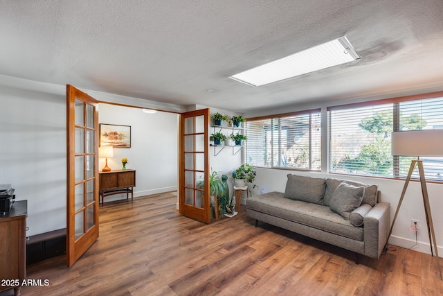 living room featuring a skylight, french doors, a textured ceiling, and hardwood / wood-style flooring