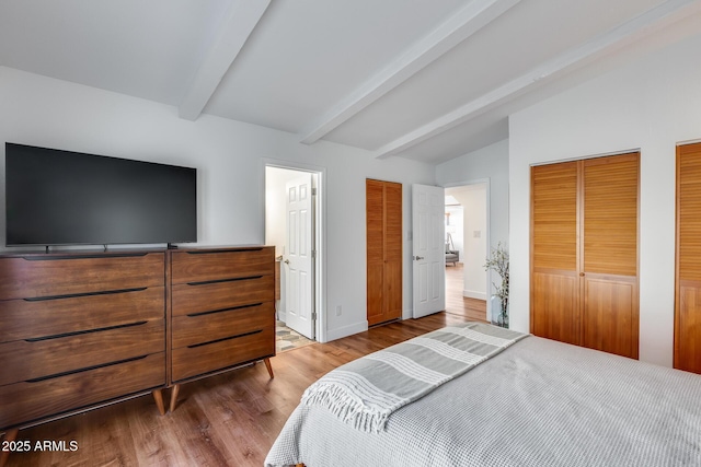 bedroom with wood-type flooring, multiple closets, and lofted ceiling with beams