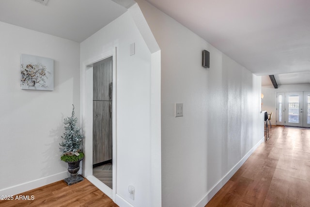 corridor featuring hardwood / wood-style flooring, beam ceiling, and french doors