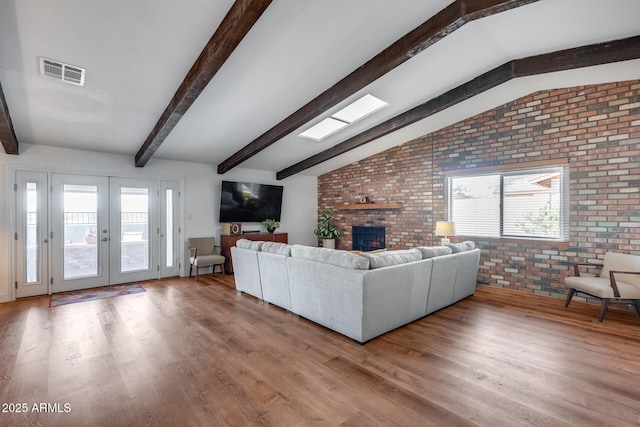 unfurnished living room with french doors, hardwood / wood-style floors, lofted ceiling with beams, and brick wall