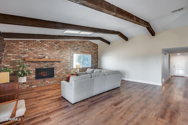 living room with wood-type flooring, vaulted ceiling with beams, brick wall, and a fireplace