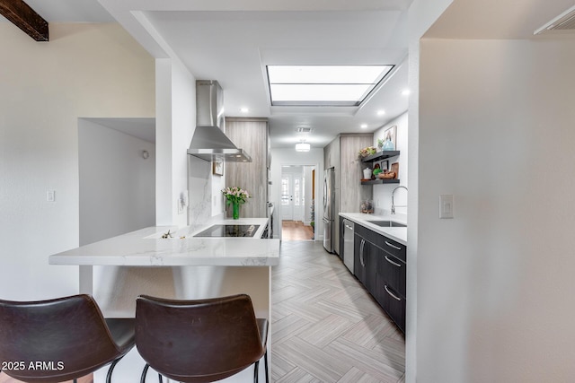 kitchen with sink, stainless steel appliances, kitchen peninsula, extractor fan, and a breakfast bar