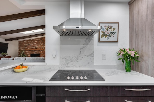 kitchen featuring vaulted ceiling with skylight, island exhaust hood, a brick fireplace, black electric stovetop, and dark brown cabinets