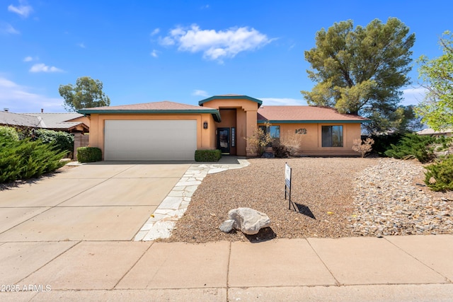 prairie-style home with a garage, driveway, and stucco siding