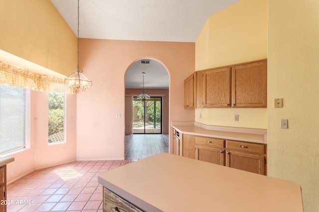kitchen with pendant lighting, light tile patterned floors, an inviting chandelier, arched walkways, and light countertops