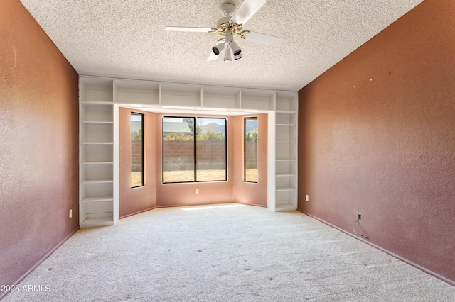 empty room with carpet floors, a ceiling fan, a textured wall, and a textured ceiling