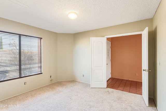 carpeted empty room with a textured ceiling and baseboards