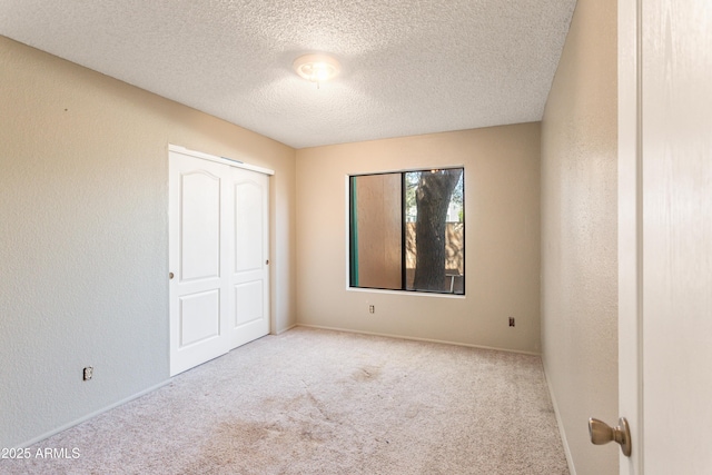 unfurnished bedroom with carpet, a textured ceiling, and baseboards
