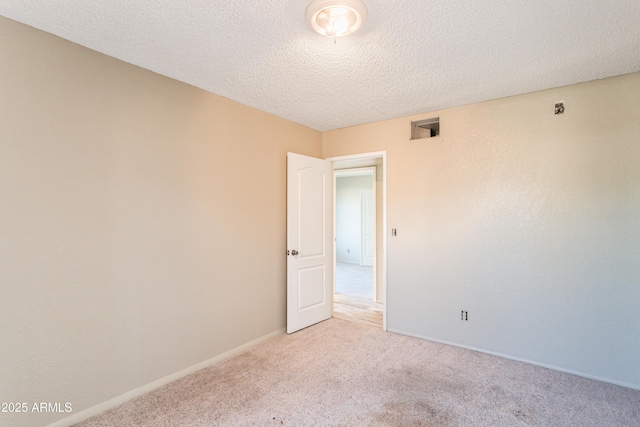 unfurnished room with baseboards, light carpet, and a textured ceiling