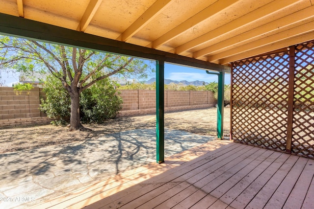 wooden terrace featuring a mountain view, a fenced backyard, and a patio area