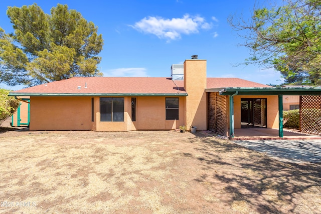 back of house with a patio area, stucco siding, and a chimney