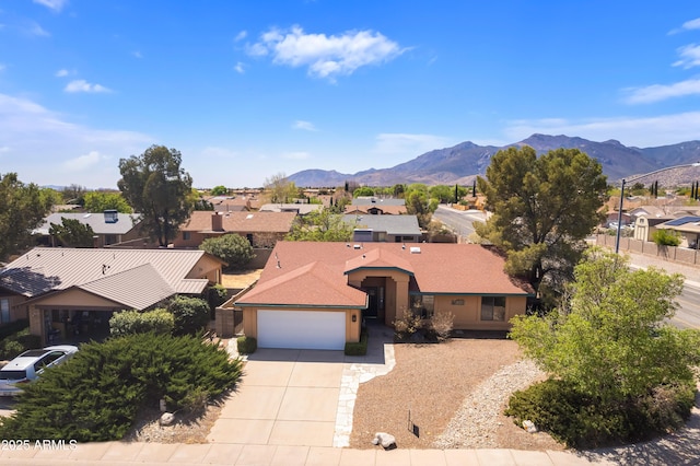 view of front of property with a mountain view, a garage, concrete driveway, stucco siding, and a residential view
