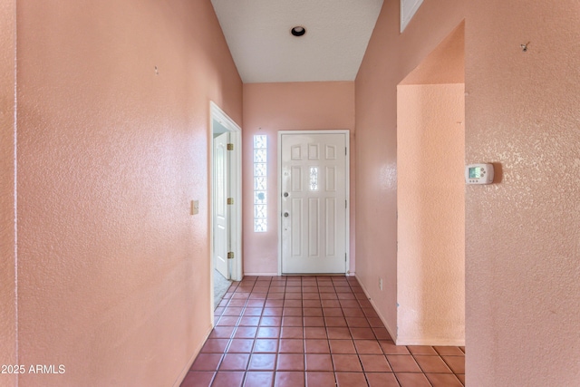 doorway to outside featuring tile patterned flooring and a textured wall