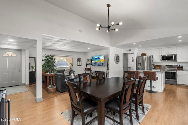 dining room with lofted ceiling, a notable chandelier, and light hardwood / wood-style floors