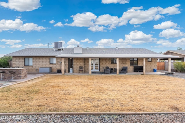 rear view of property with a patio, a yard, and a fire pit